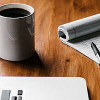 Notepad with Pen on Top Next to a Mug of Coffee