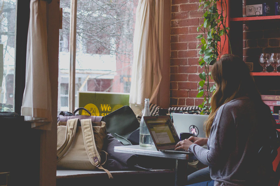 girl studying on a laptop at a desk by a window