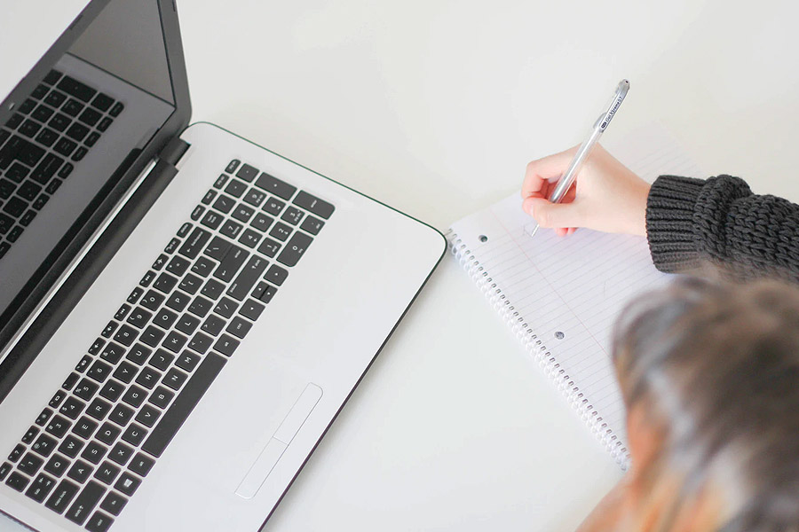 note pad and pen next to laptop