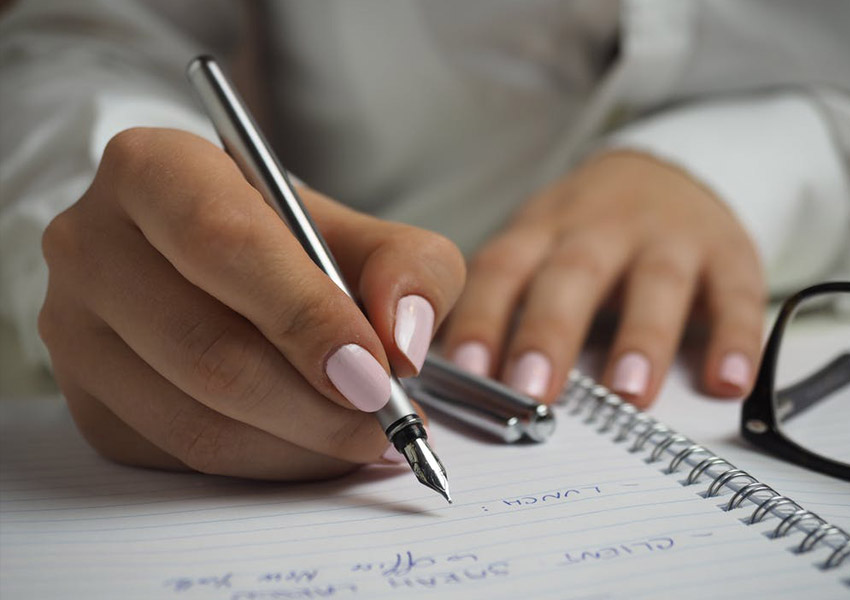 girl writing on paper glasses nails