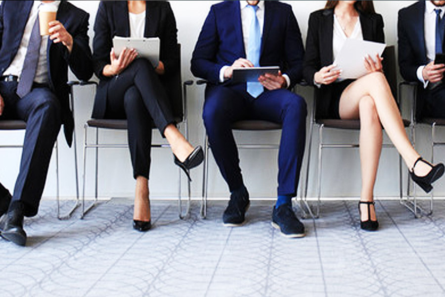 a row of people in office clothing sitting down in a line