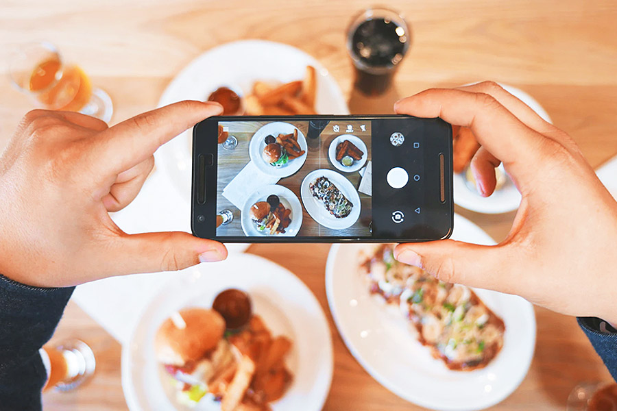 person taking a picture of a range of food with a smartphone camera