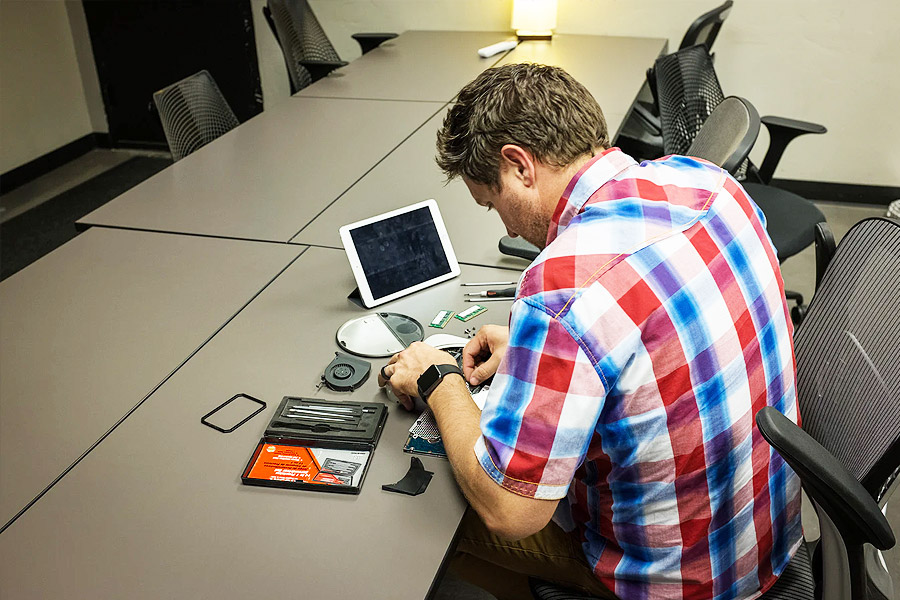 a man sat at a table fixing a device 