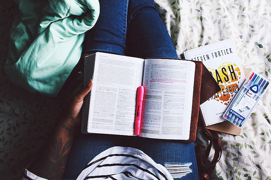 person on bed with study materials on lap 