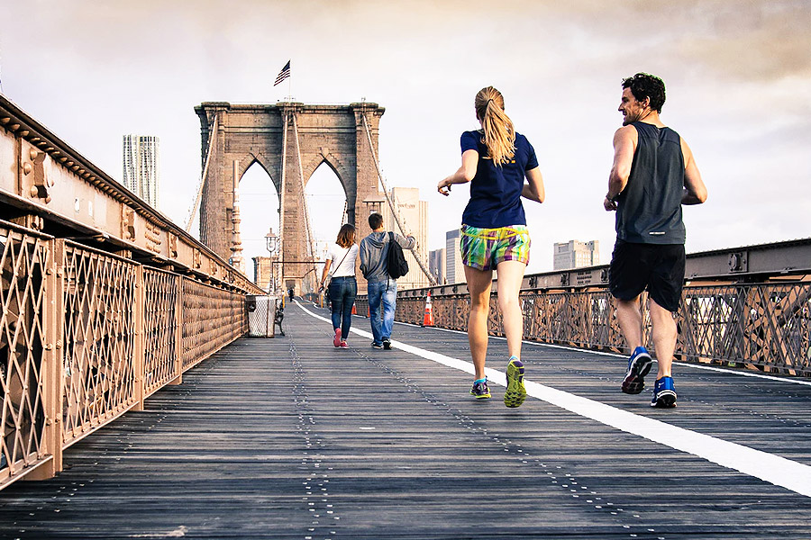 people running in gym wear along a bridge with a flag on it