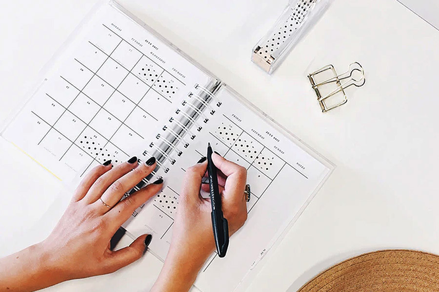 writing on a plan in a calendar on a white desk