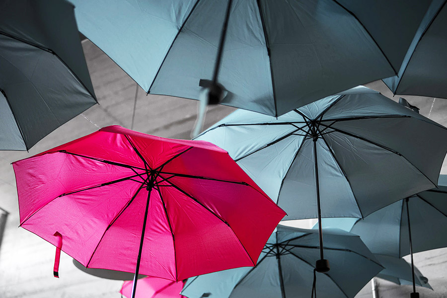 grey umbrellas with a pink one