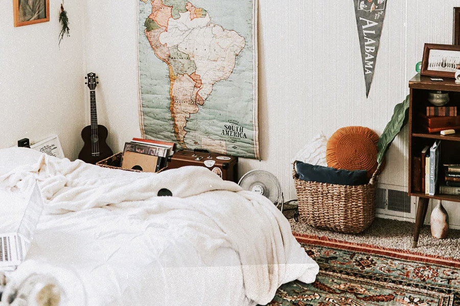 a young adult room furnished with travelling goods and a guitar