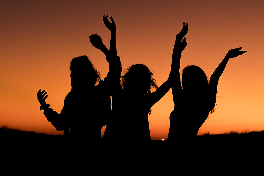 three ladies dancing silhouette in a sunset 